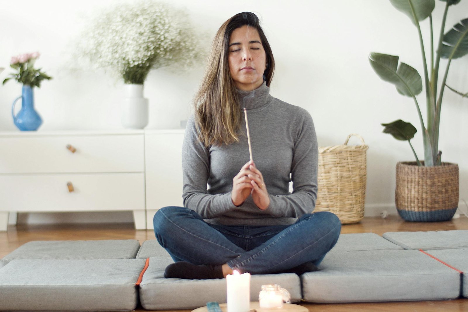 Photo of a Woman Holding an Incense Stick while Sitting